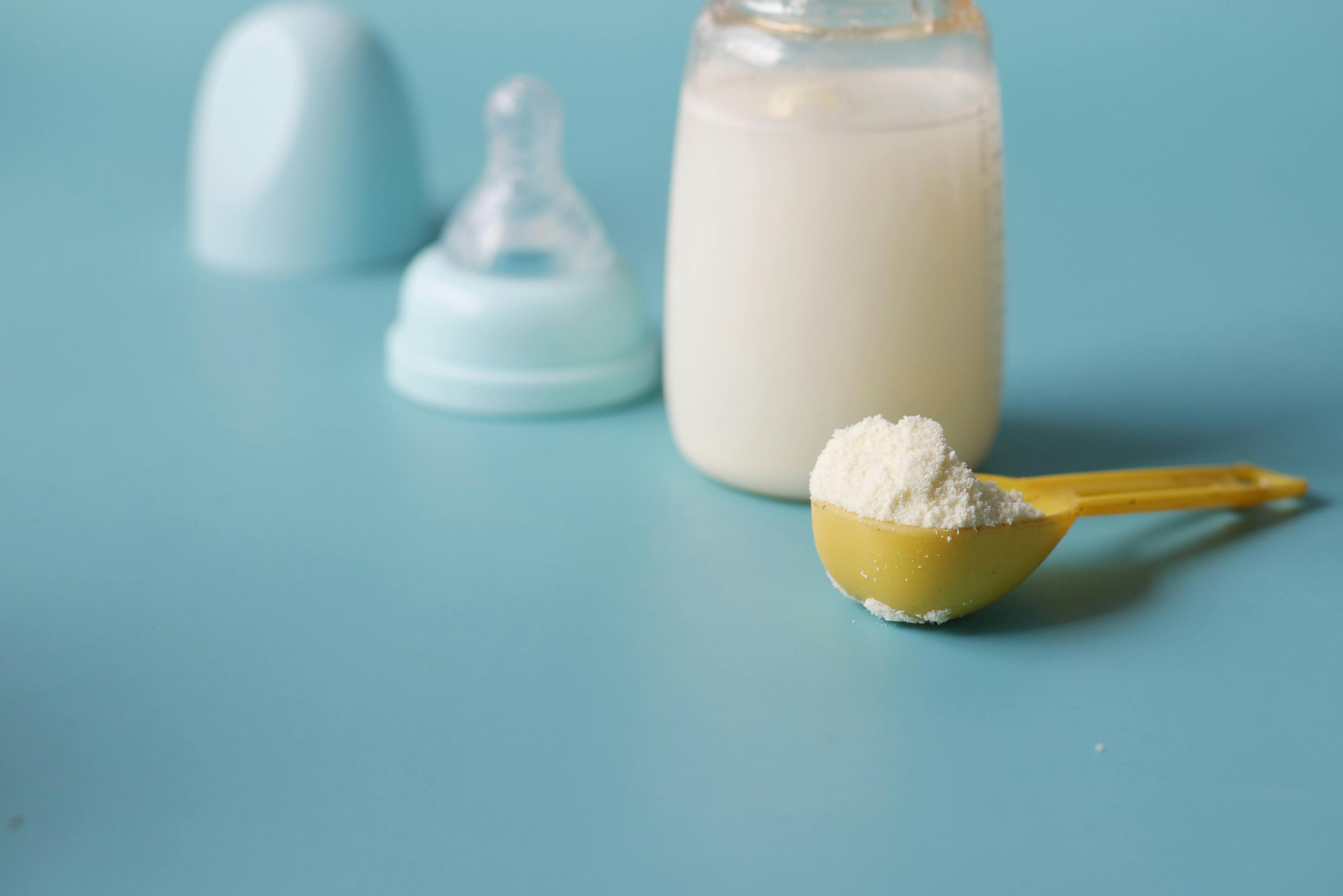 Milk powder in scoop with baby bottle